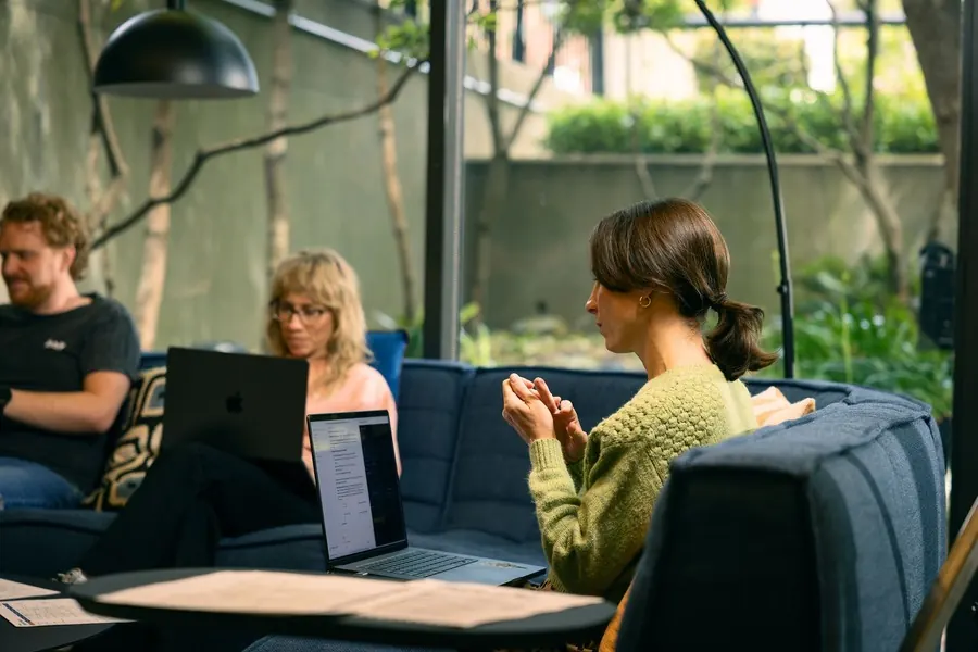 Three teammates working from the office couches