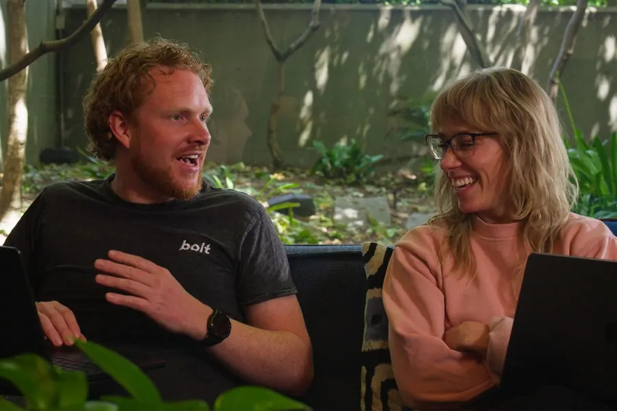 Two teammates laughing while working from the office couches